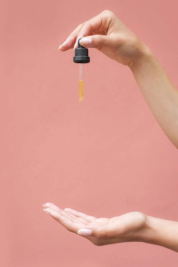 CBD Öl Dosierung pro Tropfen mit Pipette dargestellt Pipette mit CBD Öl über einer geöffneten Hand als Symbol für Dosierung, Konzentration und kontrollierte Anwendung