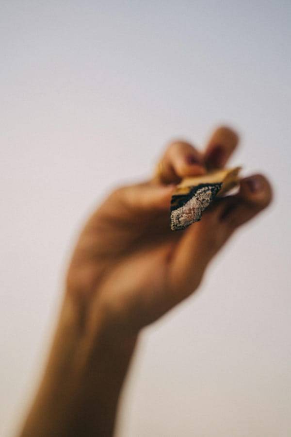 Unscharfe Nahaufnahme einer Hand, die einen gedrehten Joint nach vorne hält