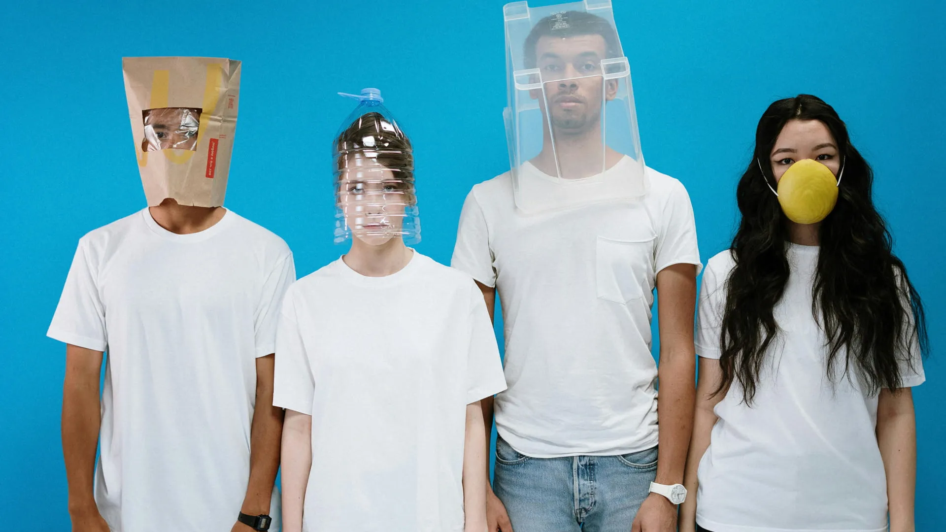 Vier junge Menschen vor blauem Hintergrund mit improvisierten Schutzmasken als Symbolbild für Alltag, soziale Einflüsse und Jugendschutz