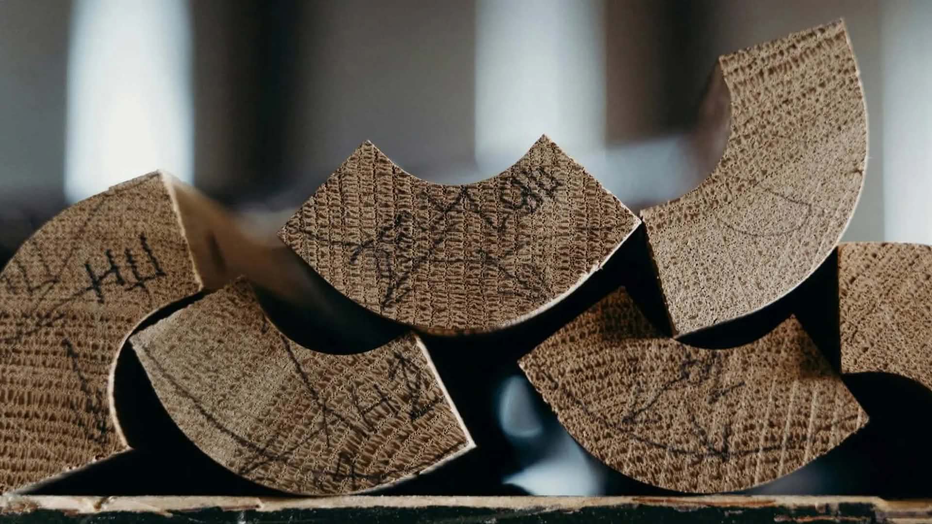 Mehrere gestapelte Holzstücke mit sichtbaren Jahresringen und handschriftlichen Markierungen auf den Schnittflächen